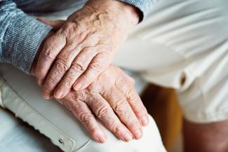 Close up of a retired couple holding hands.